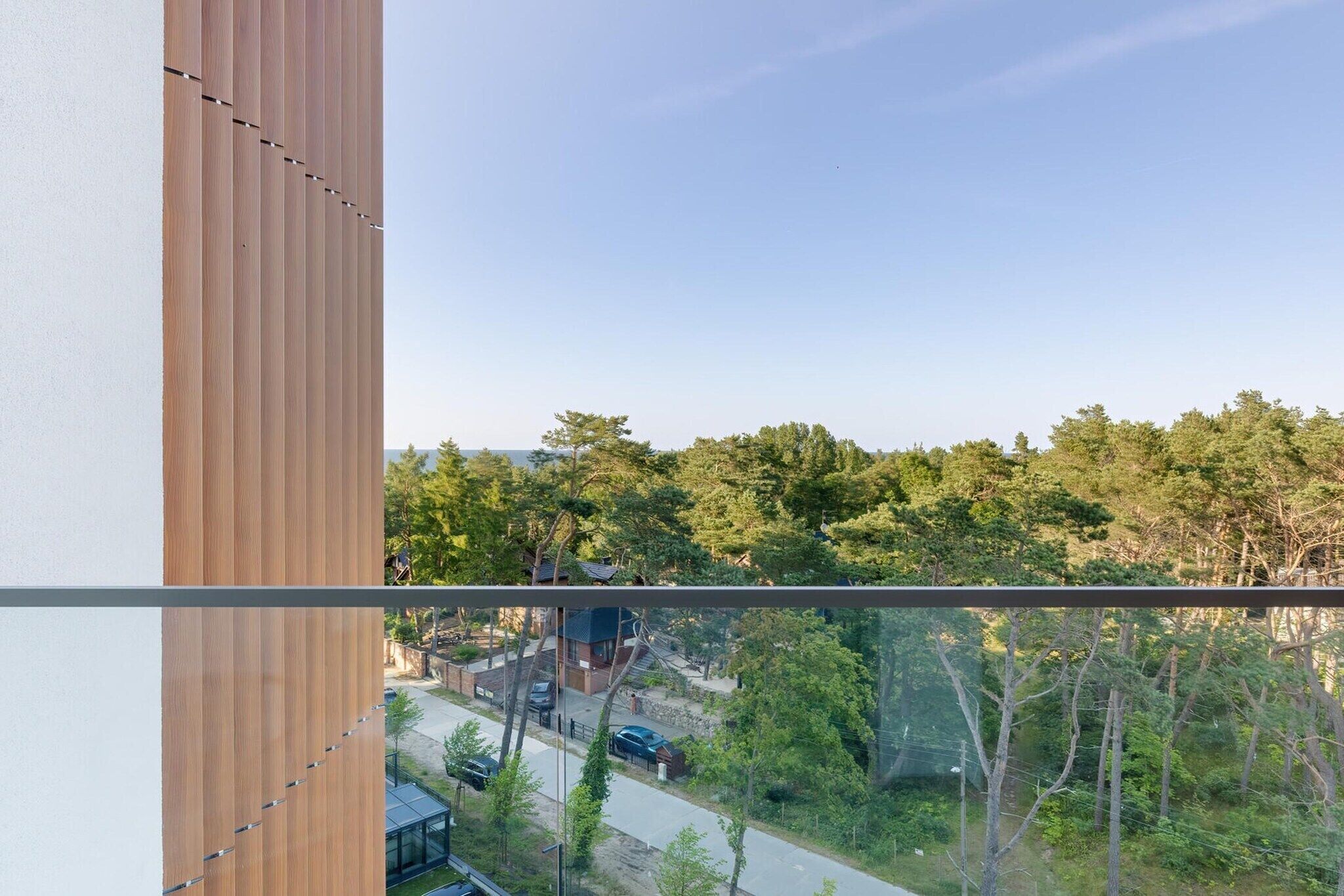 A modern building with a view of a residential area and dense trees.