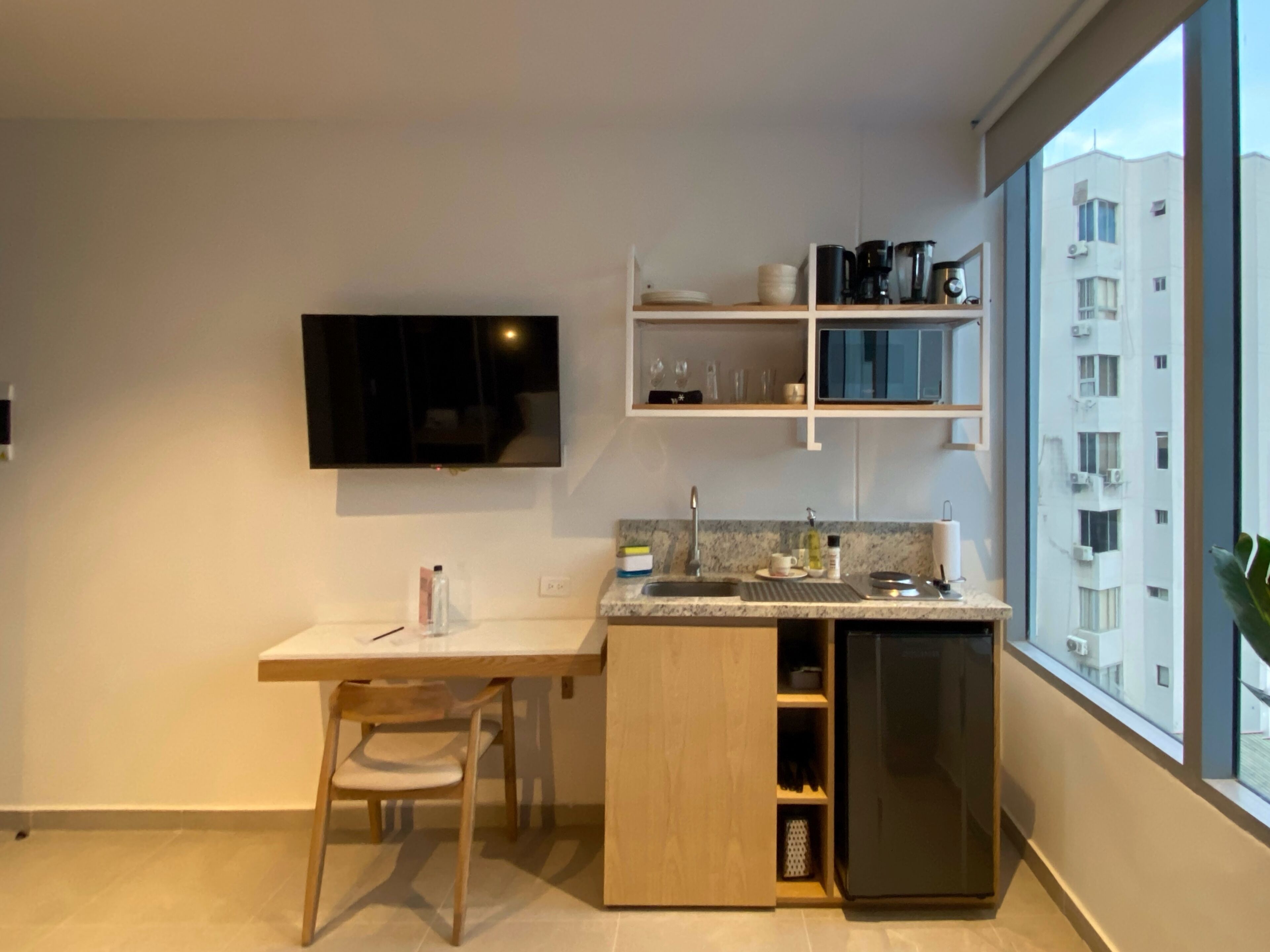 Una cocina moderna con lavavajillas integrado, una mesa de comedor de madera y un televisor montado en la pared.