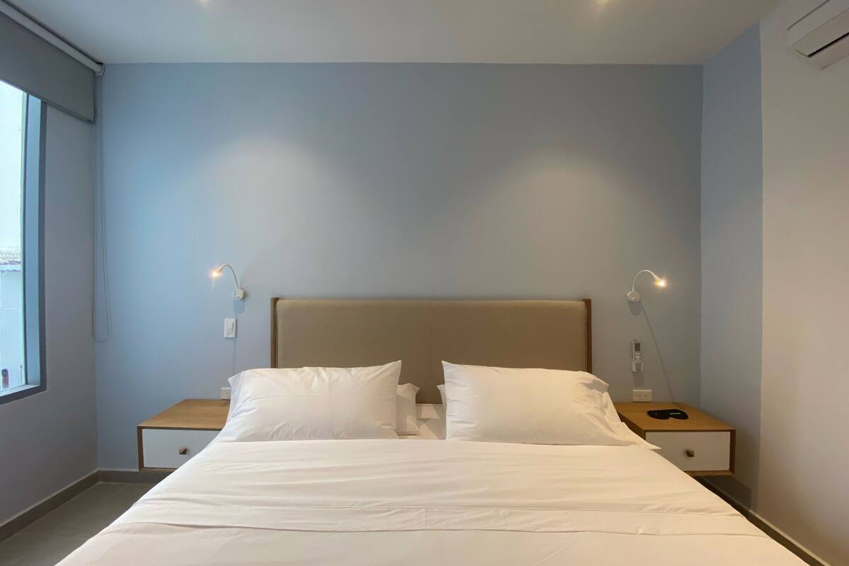 Ein Schlafzimmer mit einem Bett, zwei Nachttischen und einem Fenster.