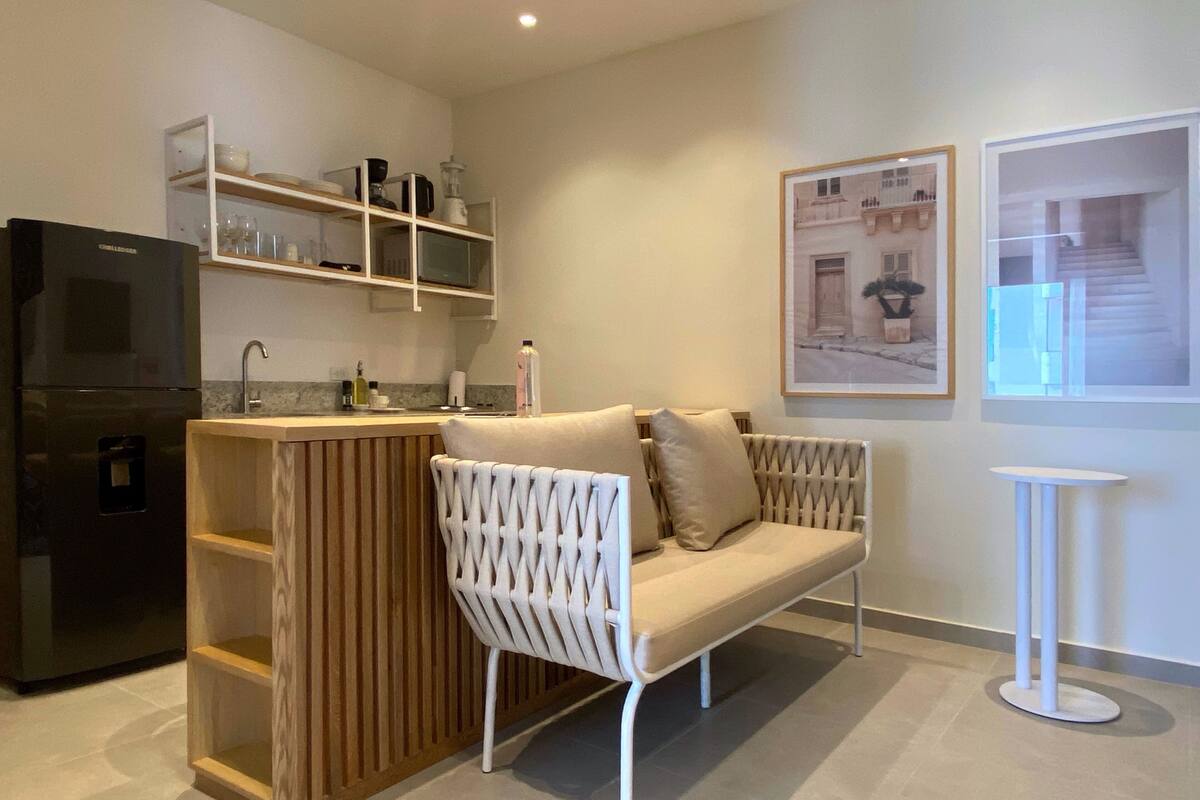 Eine moderne Küche mit einem eingebauten Kühlschrank, Holzböden, einem weißen gewebten Stuhl und einem kleinen weißen Tisch.