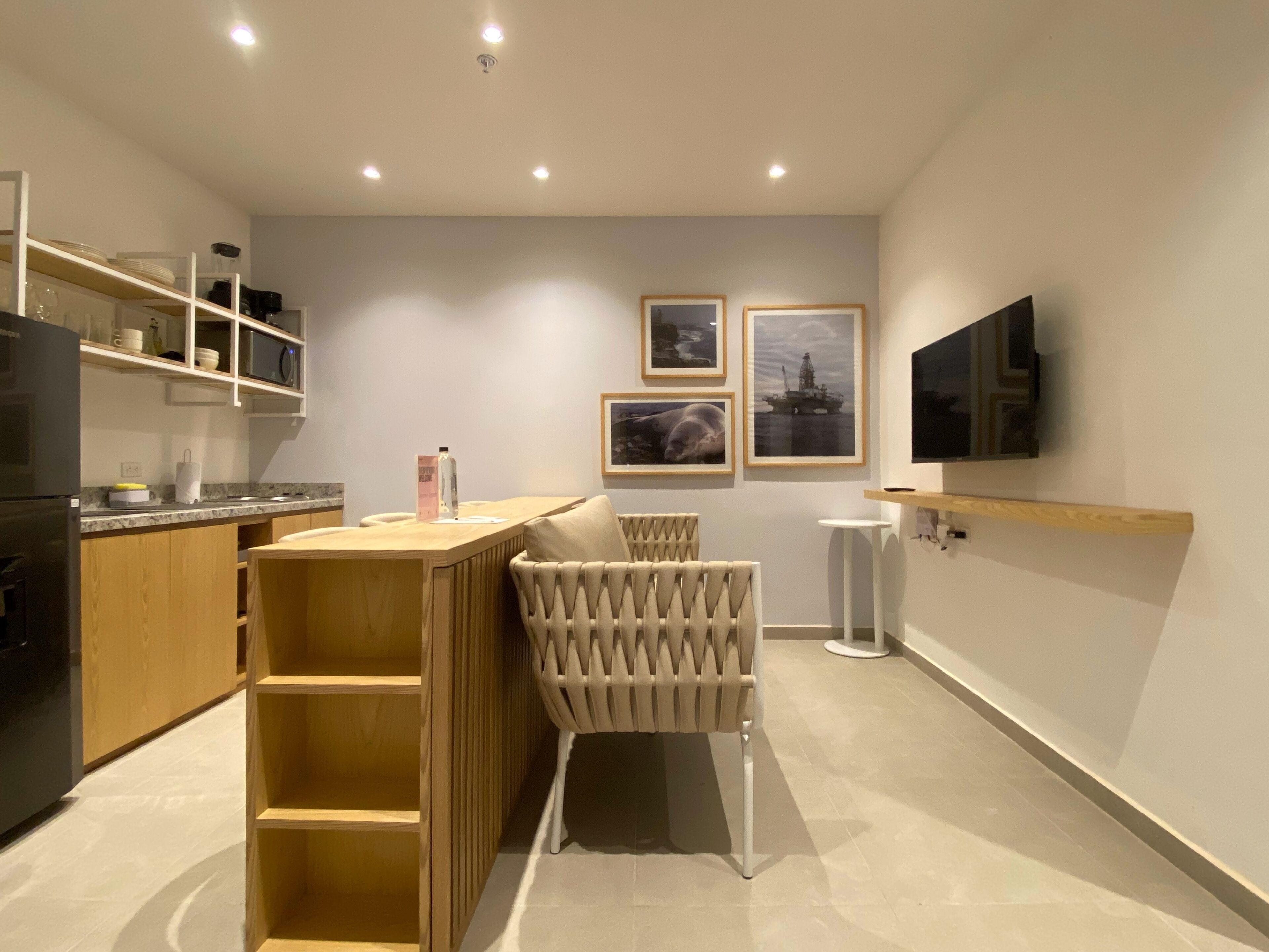 Una cocina moderna con armarios de madera, microondas integrado y una barra con una silla original.