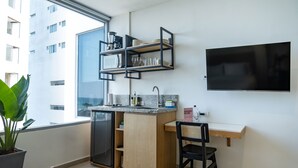 Una cucina moderna con frigorifero integrato, un piano di lavoro in legno e una sedia nera. In parete, è presente una TV e si nota una pianta in vaso.