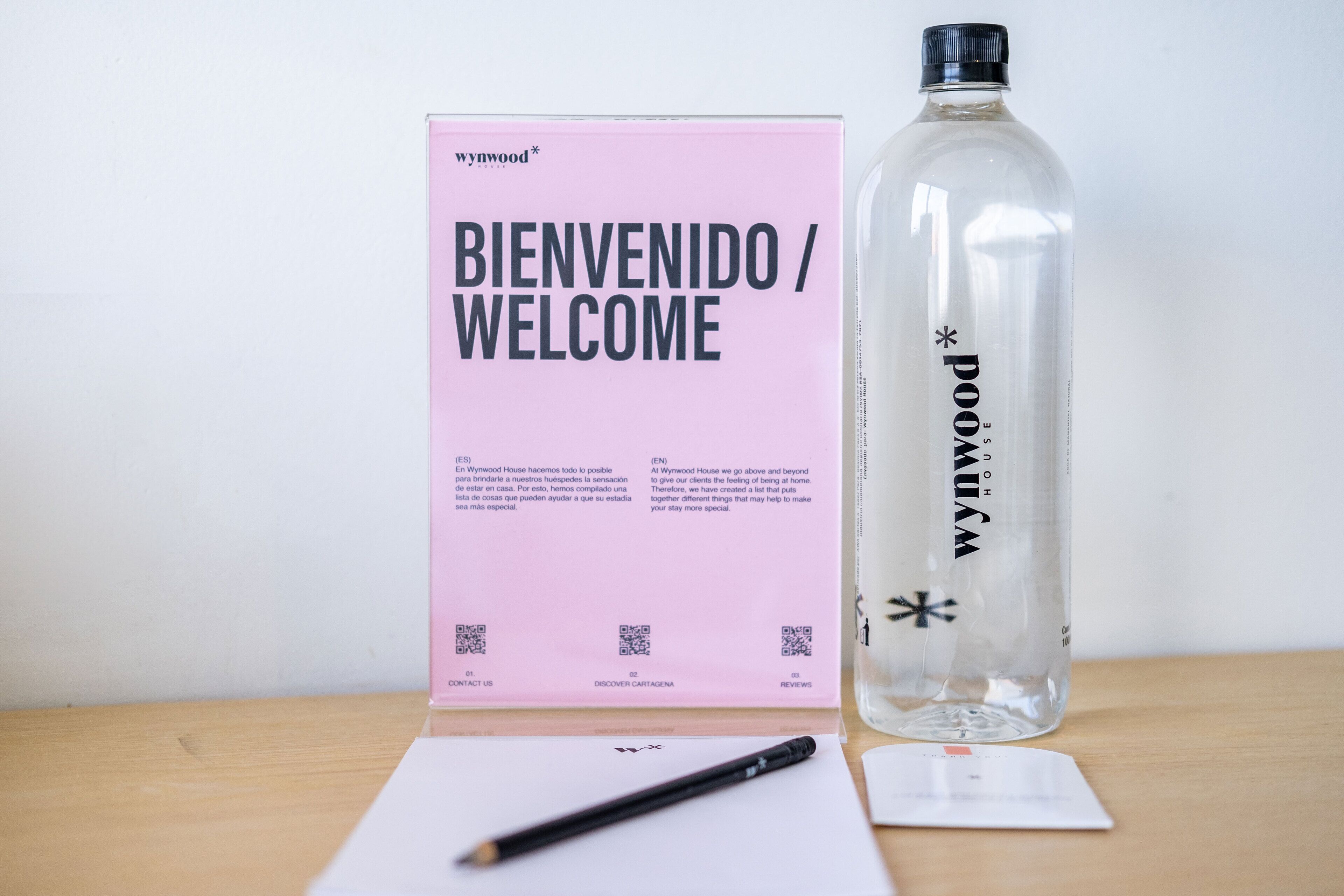 A welcome card, a water bottle, and a pen on a table.