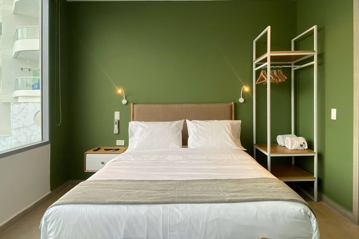 Ein Hotelzimmer mit Bett, Nachttischen, einem Kleiderschrank und einem Fenster.