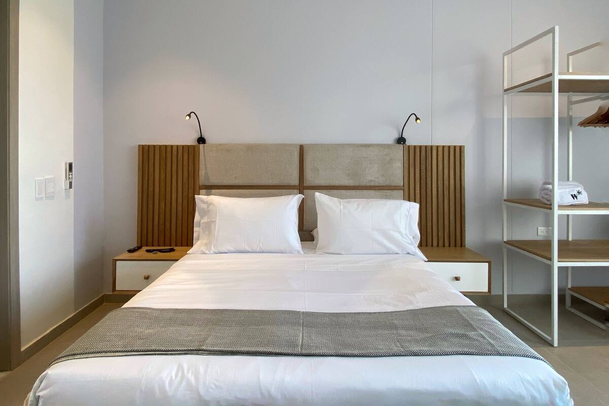 Ein Hotelzimmer mit einem großen Bett, einem Nachttisch, einem Kleiderschrank und einem Regal mit einem Handtuch.