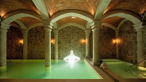 A spa area with a central pool, stone walls, and arched ceilings.