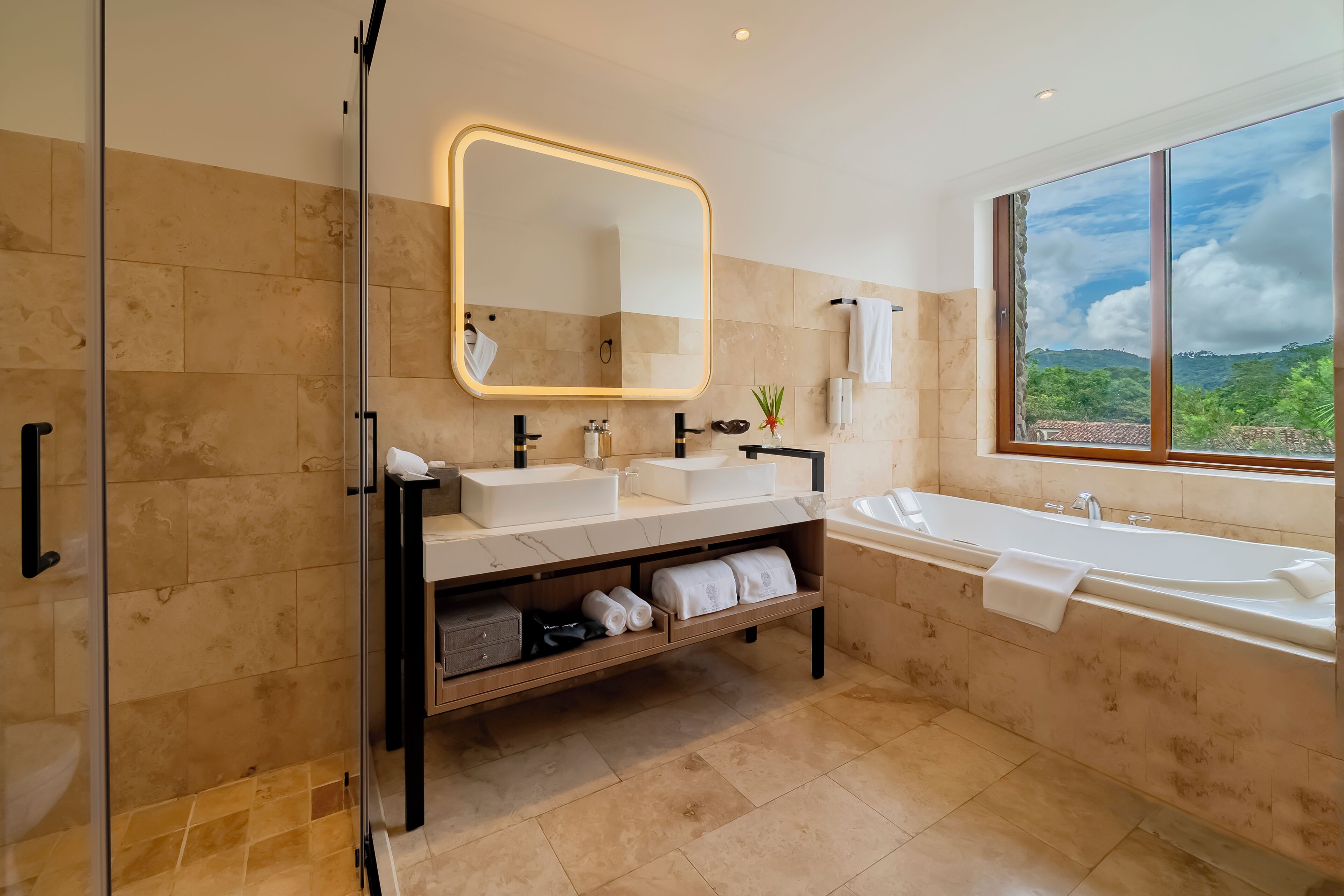 A modern bathroom with a large mirror, two sinks, a bathtub, and a shower.