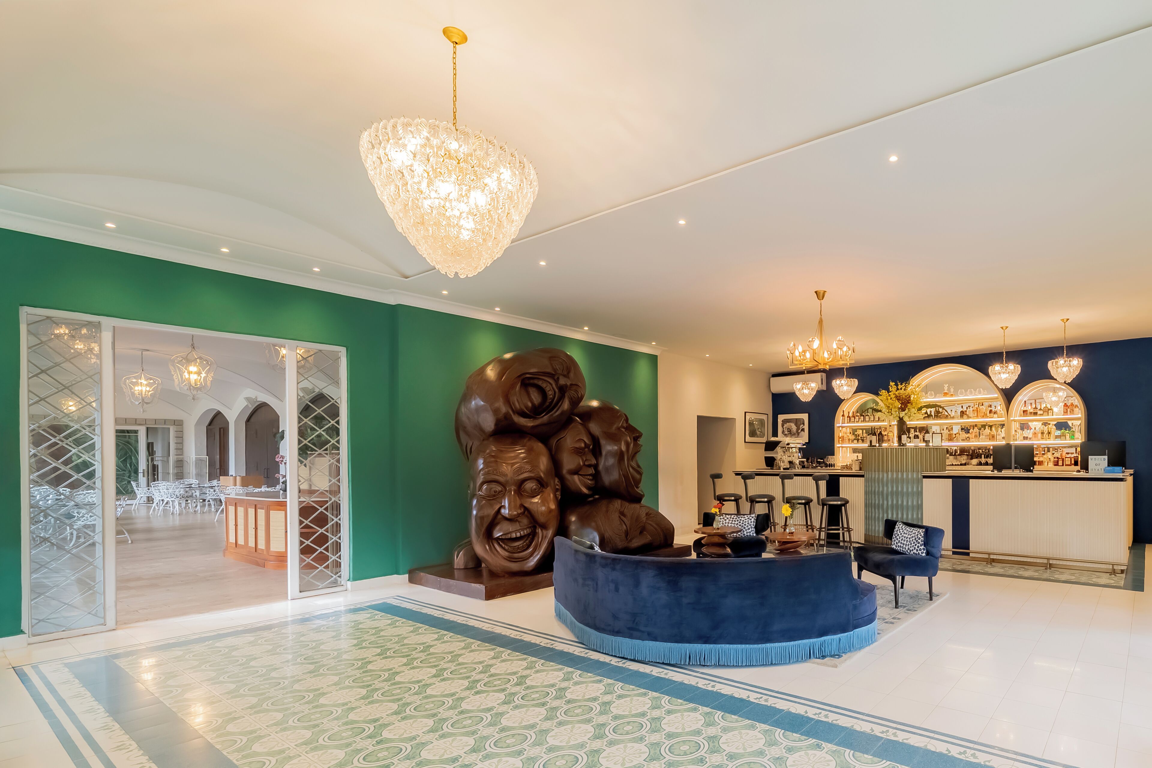 A hotel lobby with a reception desk, a large sculpture, and a bar area.
