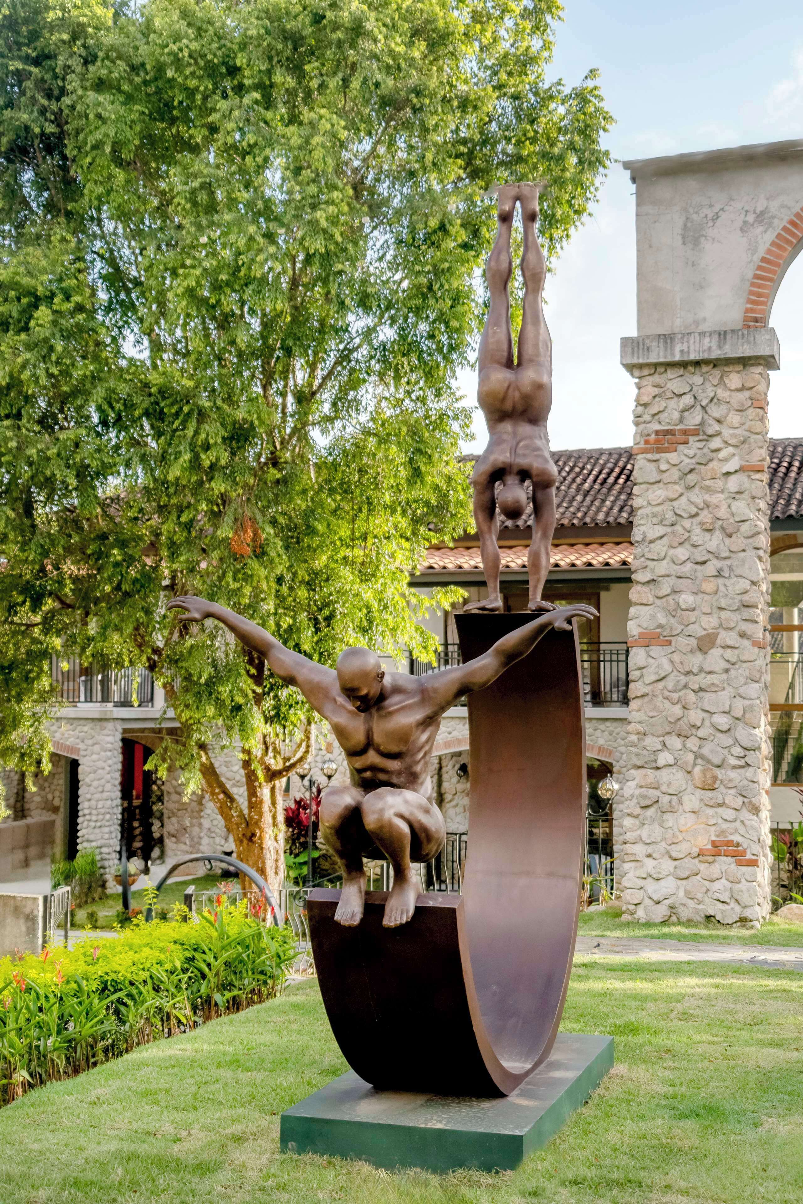 A sculpture of two figures in a garden setting.
