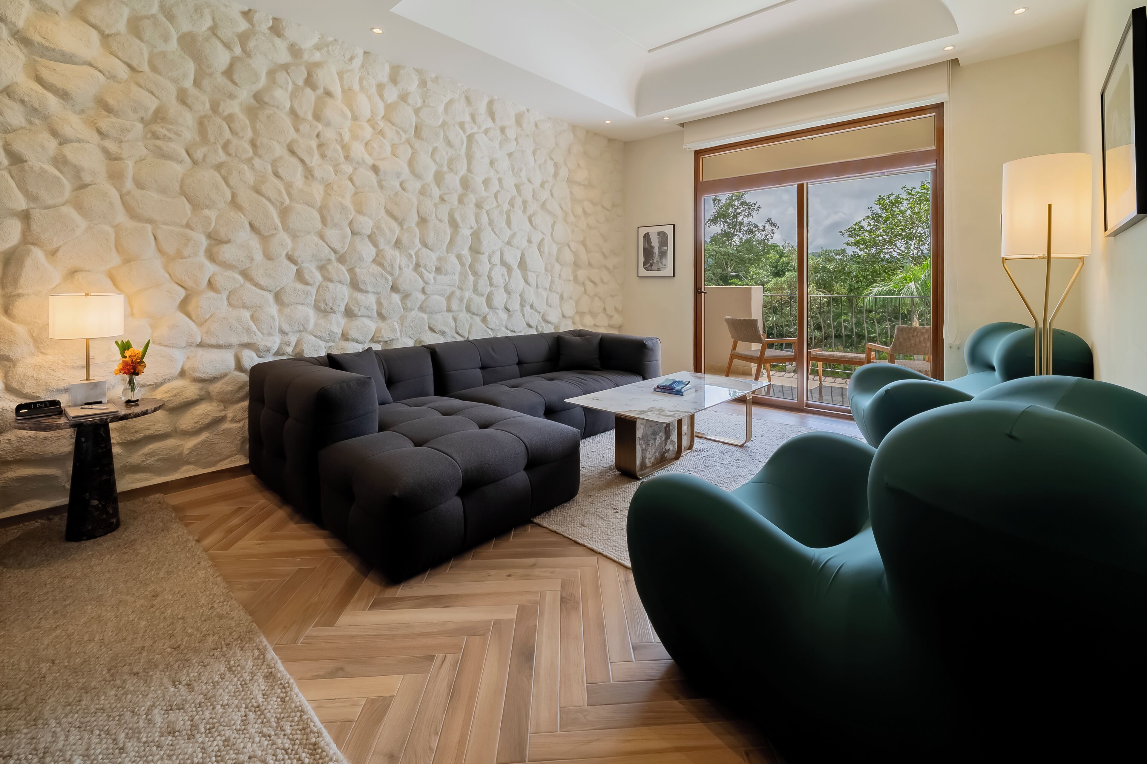 Una sala de estar moderna con una pared de piedra, un sofá modular, una mesa de centro y vistas al exterior.