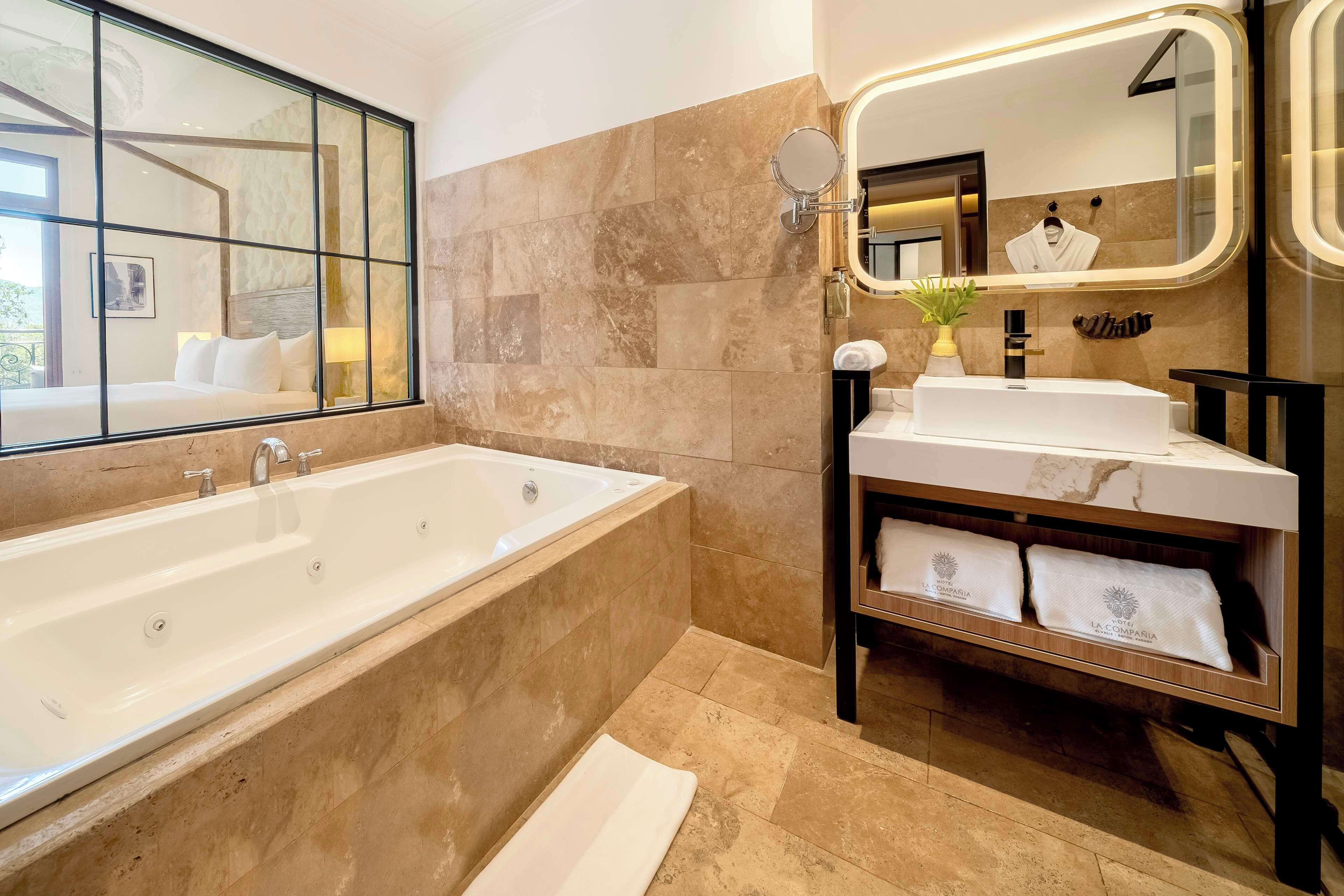 A modern bathroom with a large bathtub, a vanity with a mirror, and a towel rack.