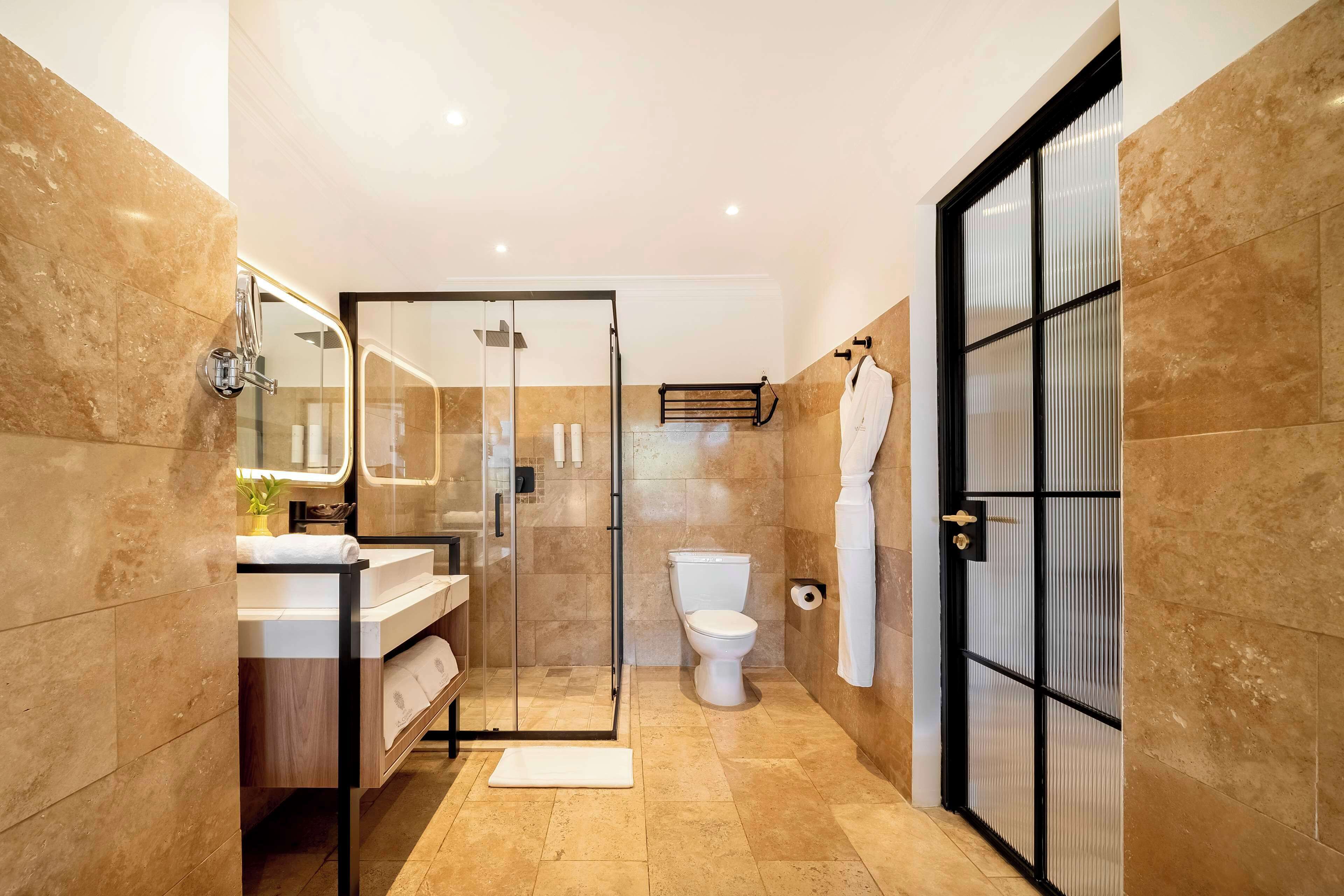 Une salle de bain moderne avec une douche à parois de verre, des toilettes blanches et un meuble-lavabo avec un miroir.