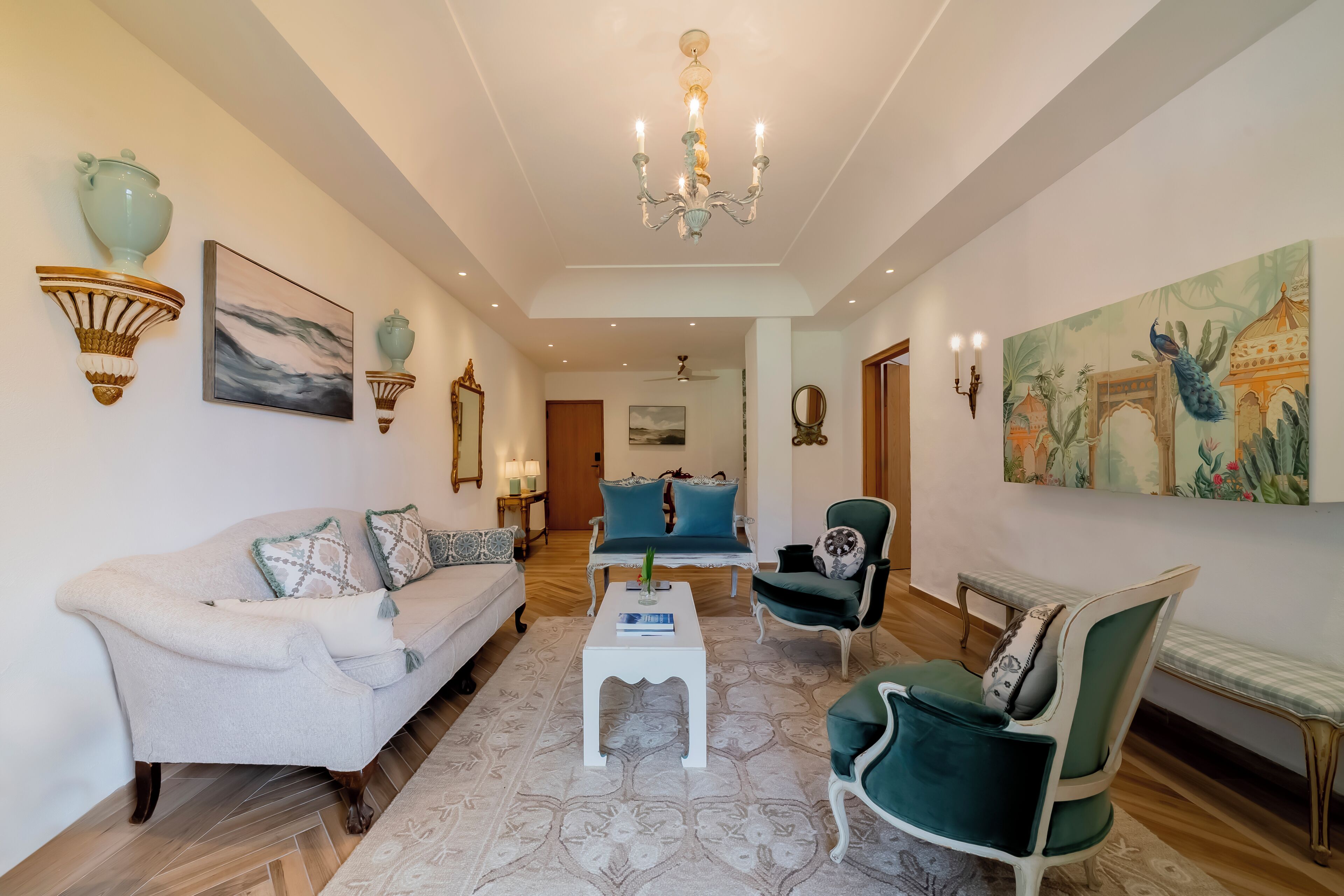 A spacious living room with a white sofa, a blue armchair, and a green armchair. A white coffee table is in the center.