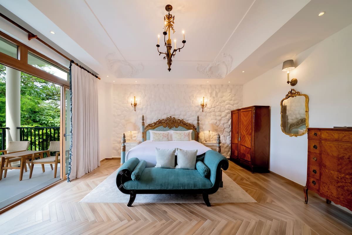 Une chambre à coucher comprenant un lit, un canapé, une commode et un lustre.
