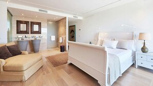 A modern hotel room with a large bed, a sofa, a bathroom with a shower, and a small desk. - Super Villa With Swimming Pool (Sant Josep de sa Talaia)
