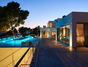 A modern house with a swimming pool, outdoor seating, and large windows.