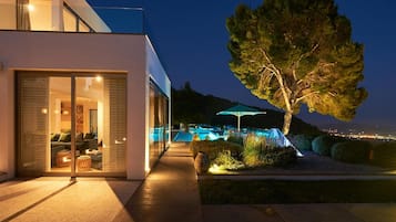 Enjoy a serene living area with sofas and a coffee table, surrounded by a lush garden and a sparkling pool.