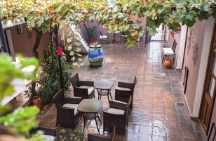 Um pátio com móveis de vime, plantas em vasos e piso de azulejos.