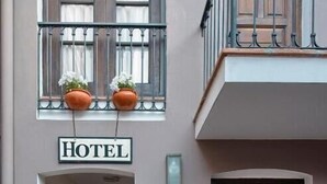 L’entrée d’un hôtel, avec un panneau, un banc et des plantes en pot.