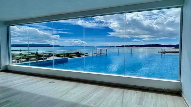 A large room with a view of a swimming pool and distant islands. - Hotel O Bayu Service Apartment (Langkawi)