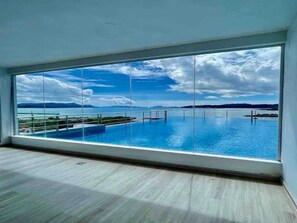 Amplia habitación con vistas a una piscina y a islas distantes.