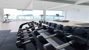 A gym with exercise equipment, a treadmill, and a view of the sea. - Hotel O Bayu Service Apartment (Langkawi)