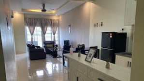 A modern living room with a sofa, TV, and a dining area with a fridge and cabinets. - Hotel O Bayu Service Apartment (Langkawi)