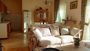 Ein gemütliches Wohnzimmer mit einer Couch, einem Esstisch und einer Küchenzeile mit Kühlschrank und Schränken.