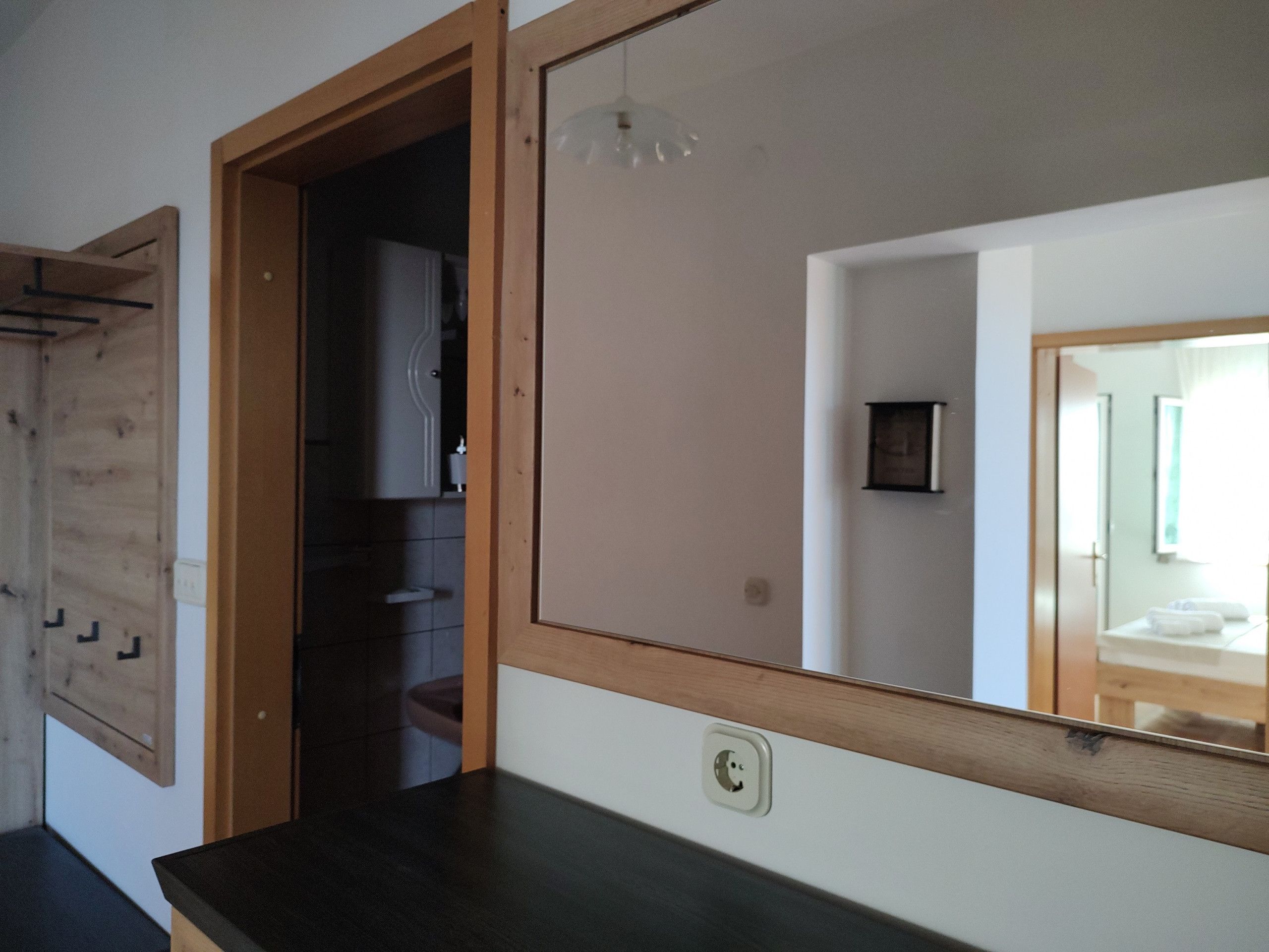 Una habitación con un armario de madera, un espejo y una encimera negra.