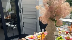 An outdoor dining area with a wooden table set for a meal, surrounded by chairs. - Villa Marantik - with outdoor pool (Bilice)