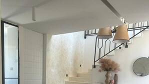 A modern living room with a sofa, a chair, and two side tables. There is a staircase with a railing and a vase with flowers on the wall. - Villa Marantik - with outdoor pool (Bilice)