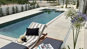 A poolside lounge area with two sunbeds, a magazine, a hat, and a potted plant. - Villa Marantik - with outdoor pool (Bilice)