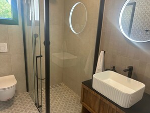 A bathroom with a glass-enclosed shower, a white sink, and a mirror with a circular light. - Villa Marantik - with outdoor pool (Bilice)