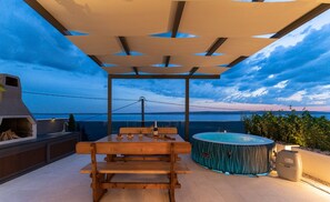 Enjoy a relaxing outdoor space with a hot tub, grill, and pergola providing shade.