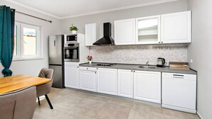 A modern kitchen with white cabinets, a stainless steel refrigerator, a microwave, an oven, a gas stove, and a dishwasher. - Apartments Alaga - A1 (Tribunj)