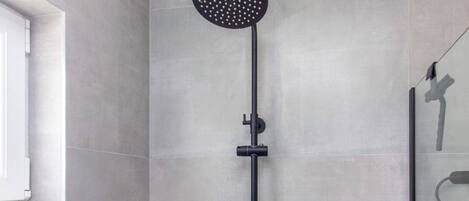 A modern shower with a round head, a handheld showerhead, and a control panel.