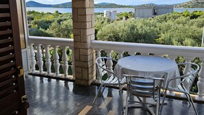 Ein Balkon mit Tisch und Stühlen, Blick auf einen See und eine Berglandschaft in der Ferne.