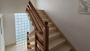 Eine Treppe mit Holzhandläufen und beigefarbenen Stufen, die zu einer Zwischenebene führen.