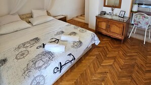 Een slaapkamer met een bed, een houten dressoir, een stoel en een spiegel.