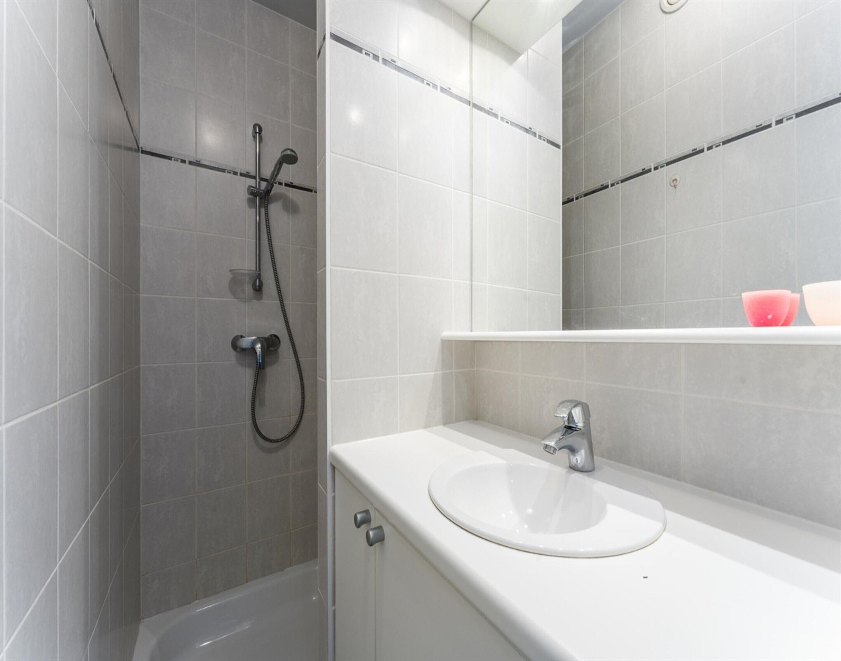 A modern bathroom with a shower, a sink, and a mirror.