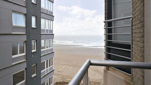 A view from a balcony overlooking a beach with a building in the foreground. - Apartment in Blankenberge Near Belgium Pier (Blankenberge)