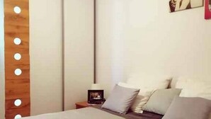 Una habitación de hotel con cama, mesita de noche y lámpara fijada en la pared.