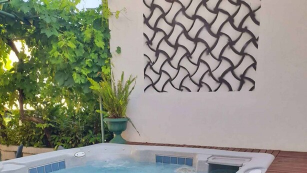 Un jacuzzi con cubierta de madera y un panel decorativo en la pared.
