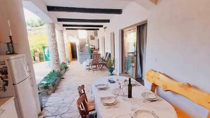 Un pasillo estrecho con una mesa lista para comer, techo de madera y vista a una habitación con una escalera.