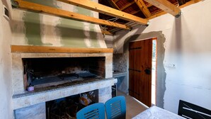 A room with a stone fireplace, wooden beams, a door, and blue chairs.