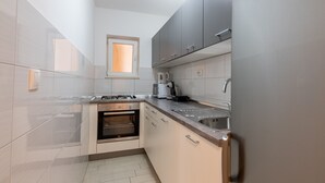 A modern kitchen with a built-in oven, a coffee machine, and a stainless steel sink.