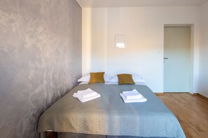 A hotel room with a bed, pillows, and a door.