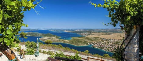 A scenic overlook with a bench and an umbrella, overlooking a coastal town and a bay.