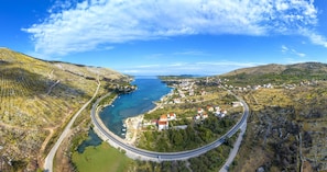 Vista aérea de un pueblo costero con una carretera sinuosa, casas y una masa de agua.