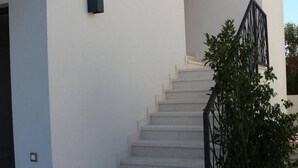 A staircase leading to a white building with black railings and potted plants.